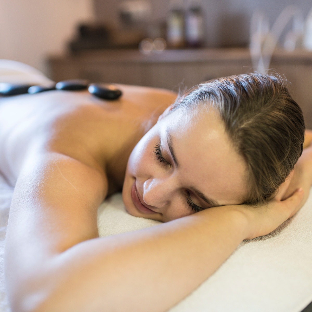 Entspannte Frau bei einer Hot-Stone-Massage im Spa des Staudacherhofs in Garmisch-Partenkirchen.