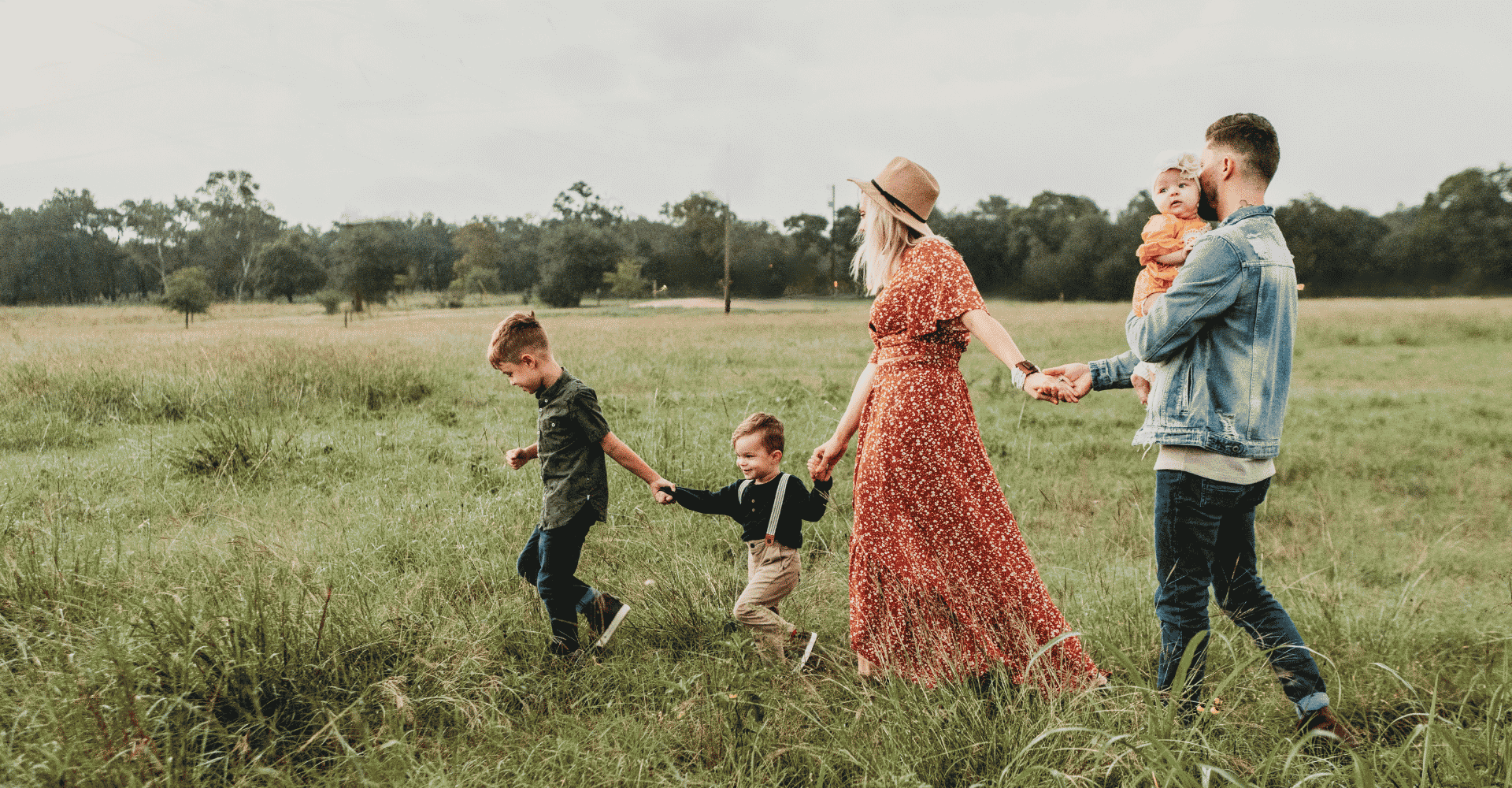 Familienausflug ins Grüne mit Kindern beim Spielen in der Natur Familie mit zwei Kindern und einem Baby auf einem Feld, glücklich beim Spielen und Erkunden der Natur.